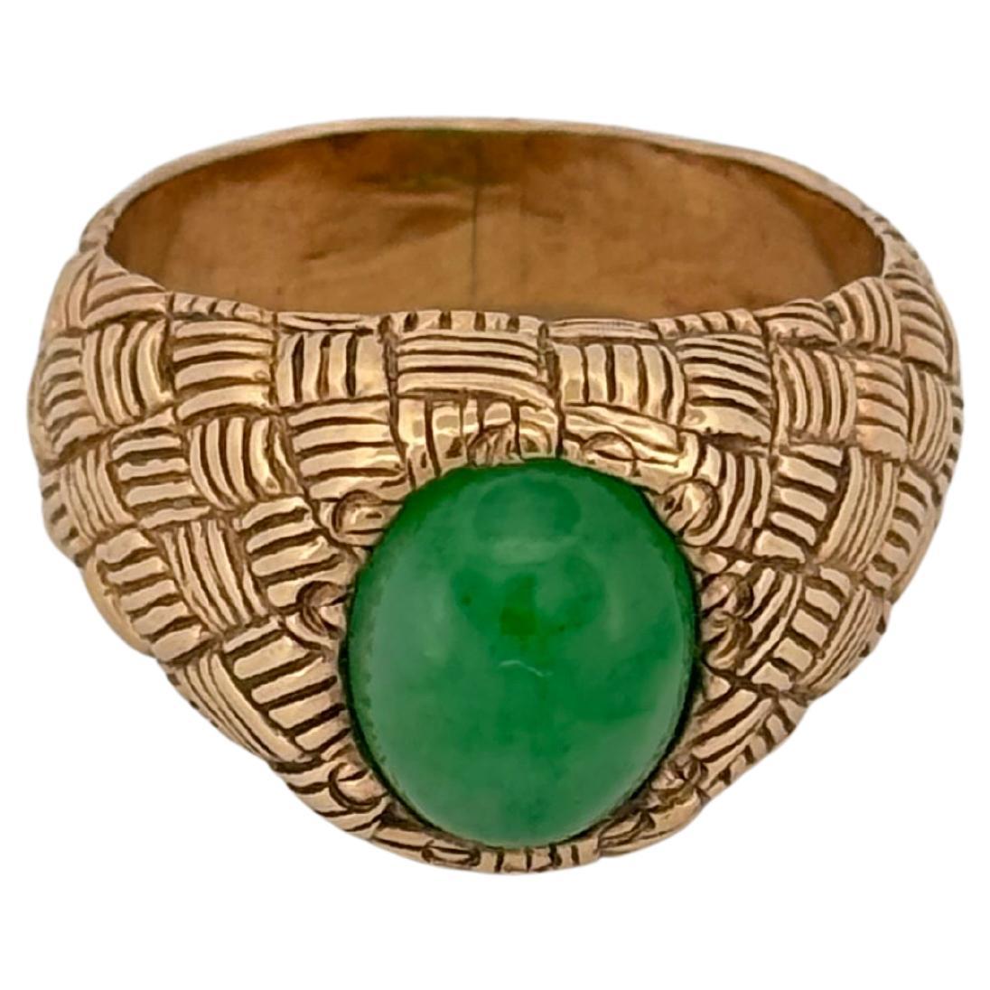 Crafted in 14K yellow gold, this distinctive ring features a finely woven basket motif that wraps gracefully around the band, showcasing expert metalwork and textural detail. At its center sits a rich green jade cabochon, smoothly polished and
