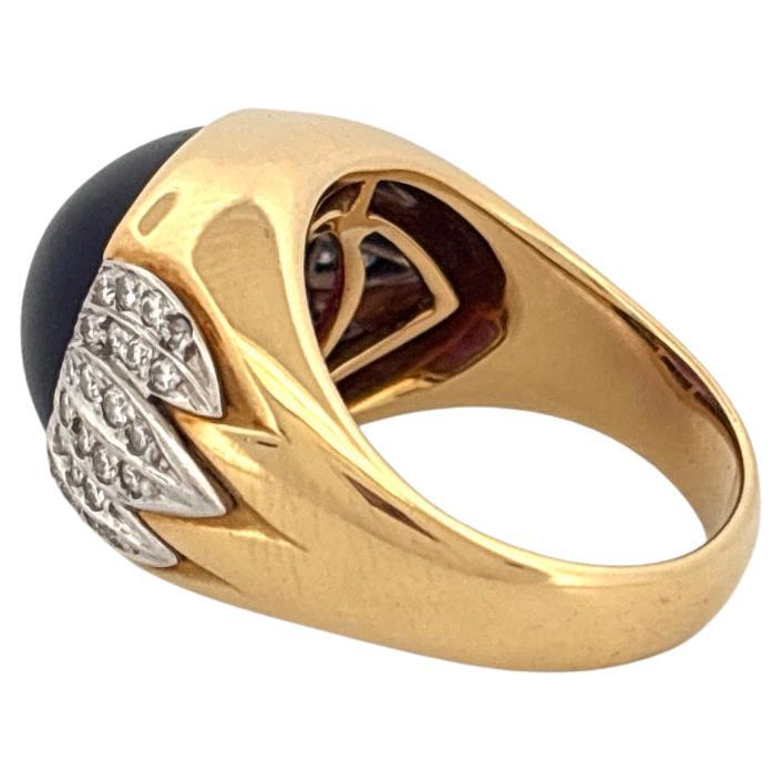 Audacieuse et sculpturale, cette bague remarquable met en valeur une améthyste cabochon de 6,80 carats richement saturée, sertie en or jaune 18 carats. La pierre précieuse d'un violet profond est encadrée de chaque côté par des motifs en éventail en