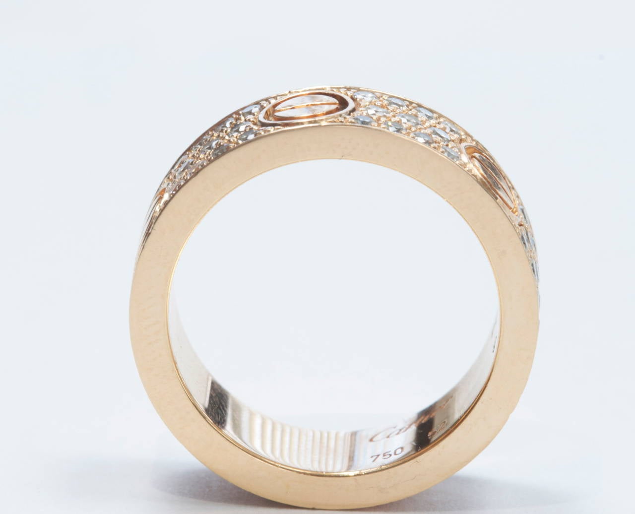 The identifiable love ring by Cartier with a modern twist. Designed with three rows of diamonds that have been separated by the classic screw engraving evenly spaced throughout. Crafted in 18k rose gold and signed Cartier. 

Where will love take