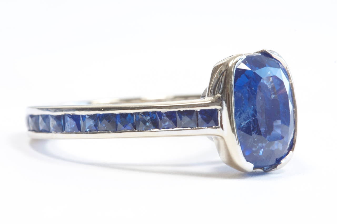 This creative ring features a 7.05 carat vivid blue sapphire that is GIA certified as Ceylon origin with no indications of heating or other treatment. It is set in an 18k white gold ring that has been crafted with 3.50 carats of blue french cut