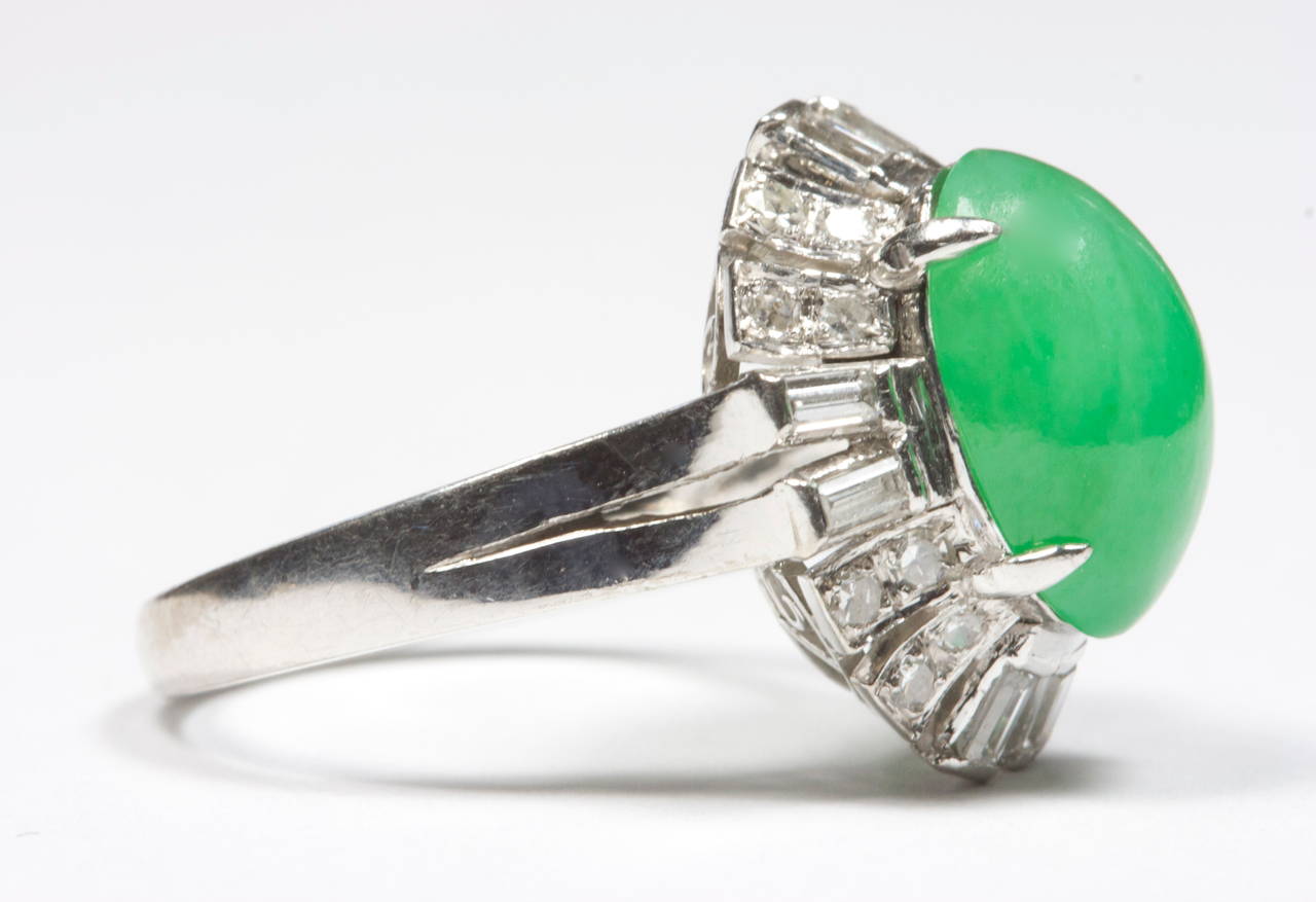 The cabochon cut jade is a pleasing green color that weighs approximately 5 carats. Set in a 18k white gold halo mounting that has been decorated with a mixture of round and baguette cut diamonds.

Size 6 and can be re-sized.