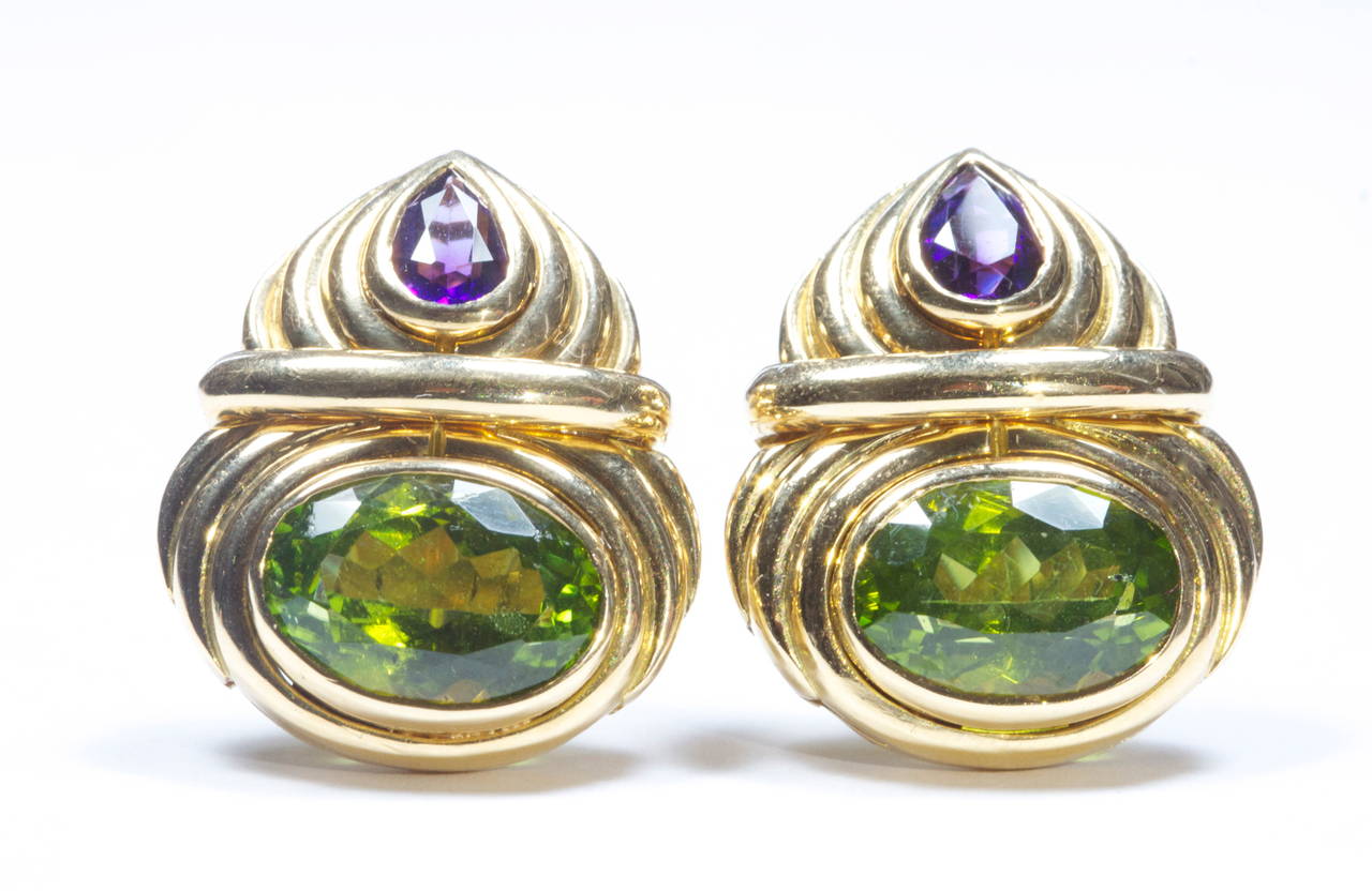 The green peridots weigh approximately 6 carats each and are nicely accented by the purple pear shaped amethysts. Crafted in contoured 18k gold.

Signed Bvlgari and numbered.
