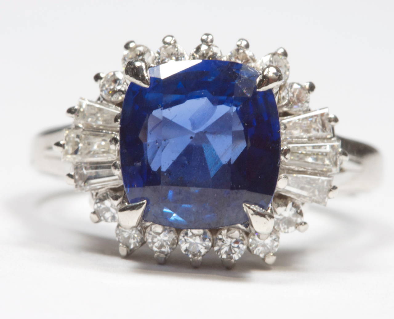 The vivd deep blue sapphire weighs 2.88 carats and has been set in a modernistic halo mounting that has been decorated with a mixture of baguette and round cut diamonds weighing 0.58 carats. Set in a platinum ring.

Ring size 6 and can be re-sized.