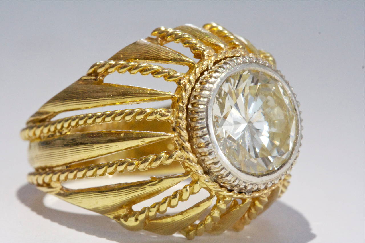 A fascinating design all comes together to feature a bezel set 3 carat round brilliant cut diamond. The diamond displays a nice warm yellow hue adding a unique charm to the stone. The jeweler has made the ring with a combination of rope motifs and
