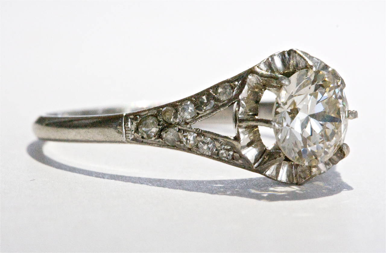 A dazzling engagement ring featuring a 1.02 carat brilliant cut diamond.  Surrounded with a ring of platinum that reflects light and makes the center stone appear larger.  The ring is hand crafted in platinum and designed with four rows of brilliant