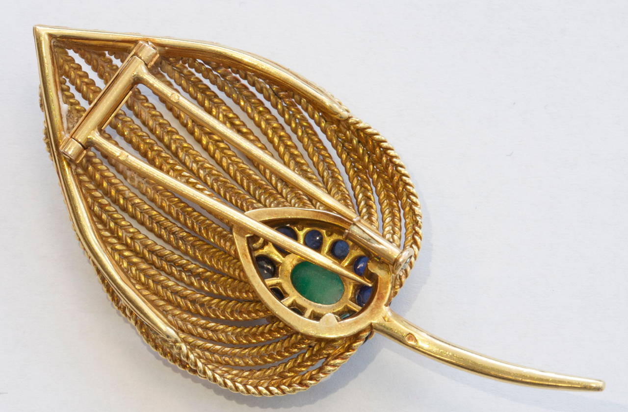 A true piece of jewelry with an elegance that you only find from France. The piece has been created with a striking color combination with the combination of a cabochon green emerald surround by round blue sapphires. Crafted in 18k gold that has