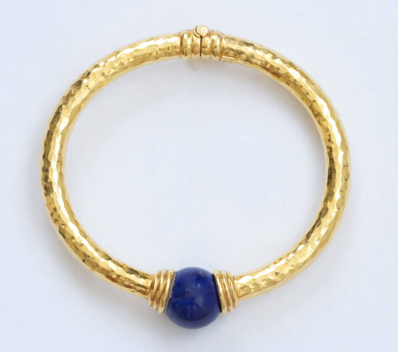 A beautiful hammered gold bracelet with a spherical ball of lapis lazuli acting as a clasp creating a true Greek design from Ilias Lalaounis. The bangle bracelet easily opens on one side of the round lapis making it freely slide onto the wearers