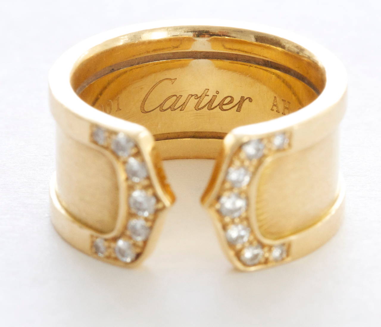 Cartier, elegant and timeless. The ring has been designed with 14 near colorless diamonds that form the classic C motif on either side. Crafted in 18k yellow gold. Signed Cartier and numbered.

Size 50.