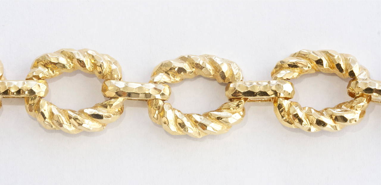 An easily identifiable design from the American jewelry designer David Webb. With the classic hammered gold look that is molded into oval shapes and  linked together with an infinite twisting effect. The unique feature  is the ability to  place  a