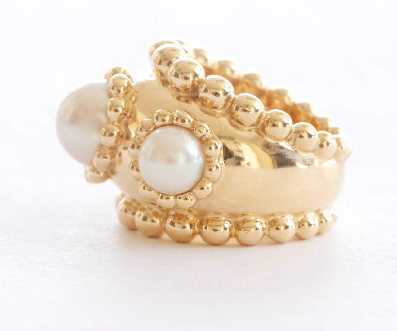 An identifiable creation from Chanel. Created with 3 white cultured pearls, a staple of Chanel jewelry. The pearls as well as the band of the ring have been outlined with perfectly spherical balls of 18k yellow gold. 

Signed Chanel with the