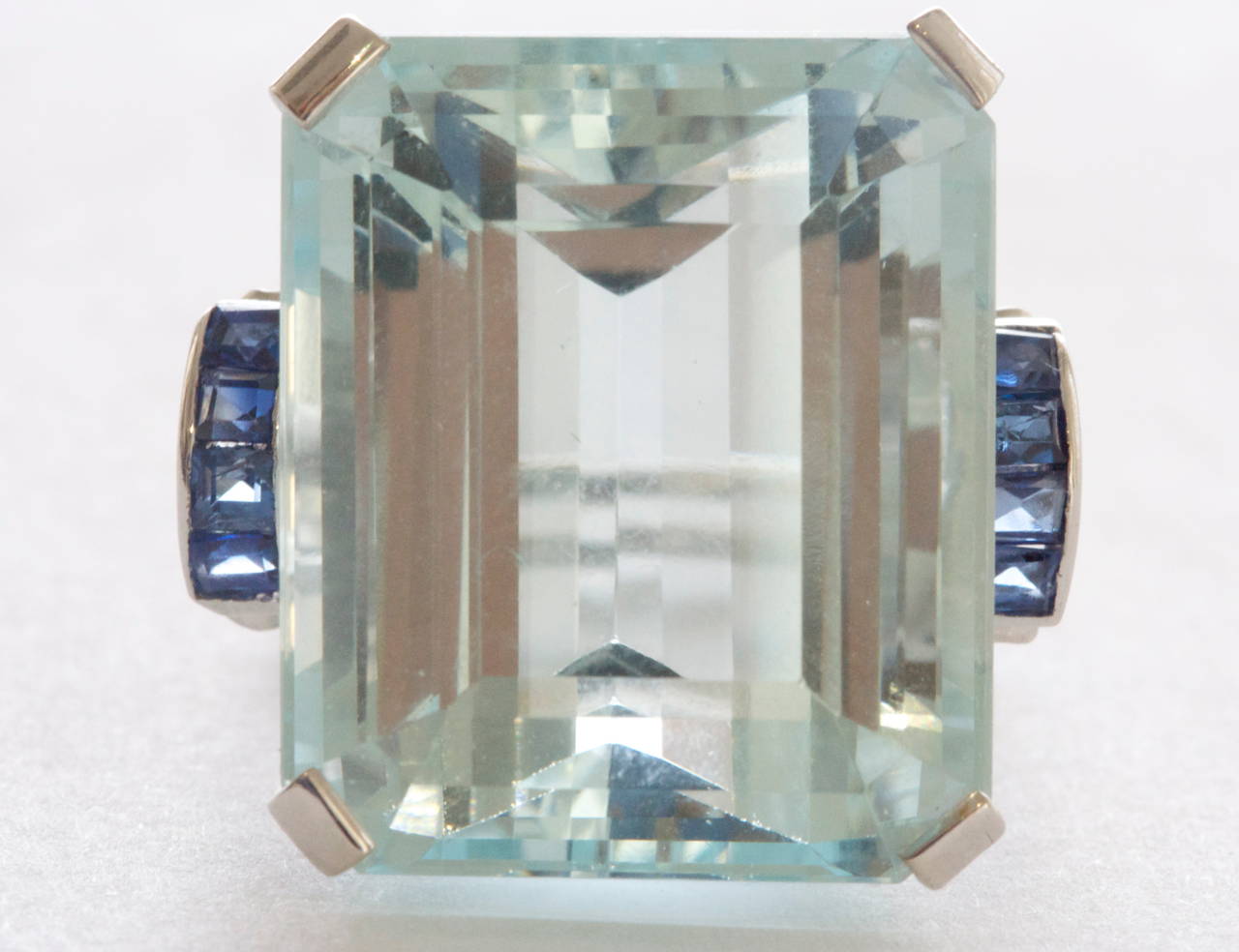 The center stone is a 31 carat lively sky blue aquamarine. Accented by square cut deep blue sapphires. Set in a hand crafted art deco platinum ring.

Ring size 7 and can easily be resized
