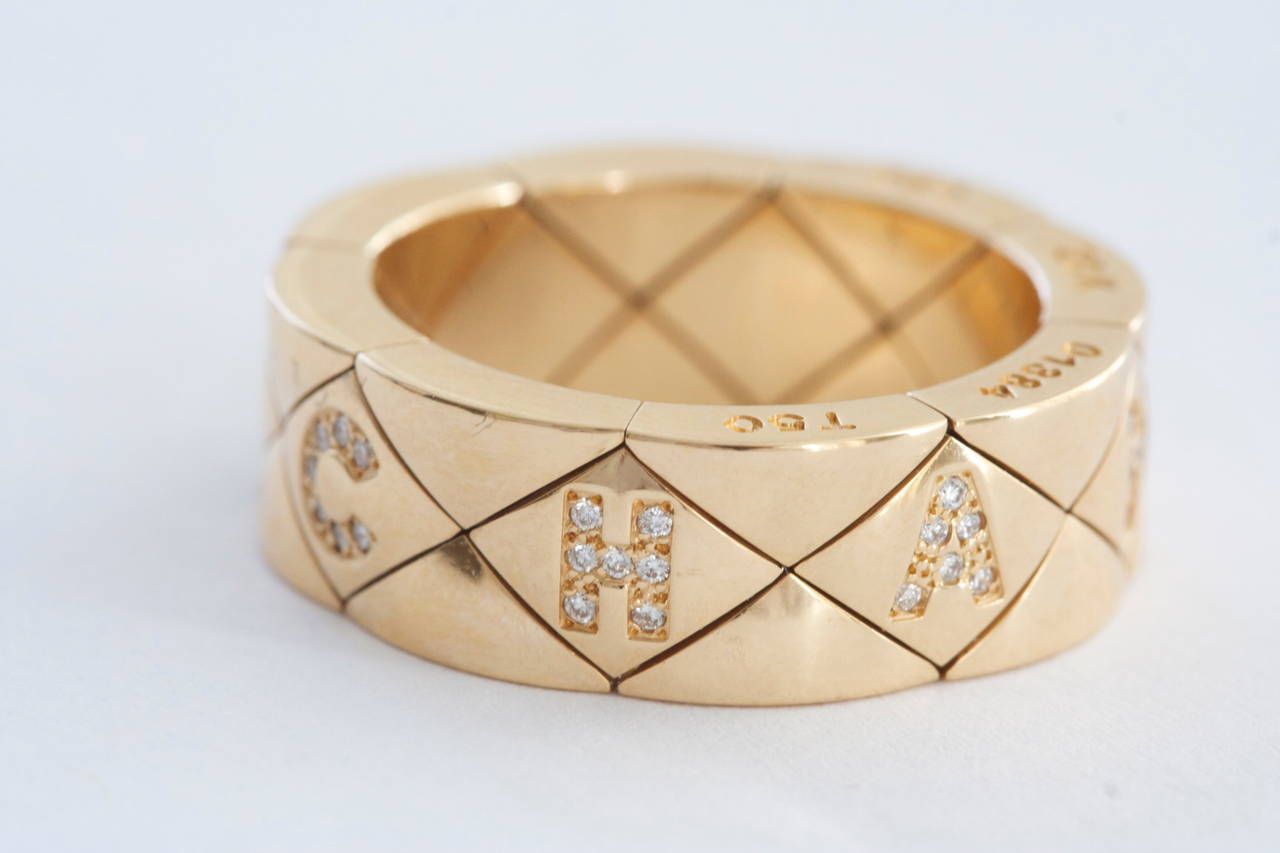 Chanel has used symmetrically criss-crossing lines to create a mesh design where they have perfectly fit the iconic Chanel name. The name is spelled out with white, clean diamonds. Created with 18k gold and signed Chanel. 

Ring size 6 and can be