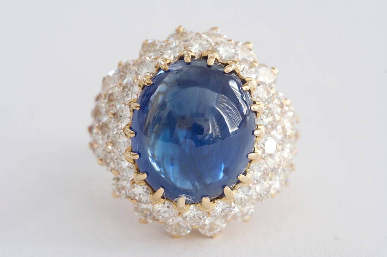 The cabochon sapphire is approximately 17 carats displays a lively deep blue color and is translucent. There are 48 round brilliant diamonds surrounding the sapphire and weighing approximately 5.50 carats. The diamonds are very white E, F color and