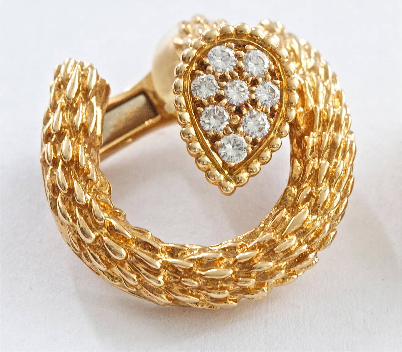 The highly desirable yellow gold snake collection from the French jewelry house of Boucheron. The designer has textured the gold to replicate the scales of a snake. There are 16 white, clean diamonds weighing approximately 0.48 carats.  In 18k gold.