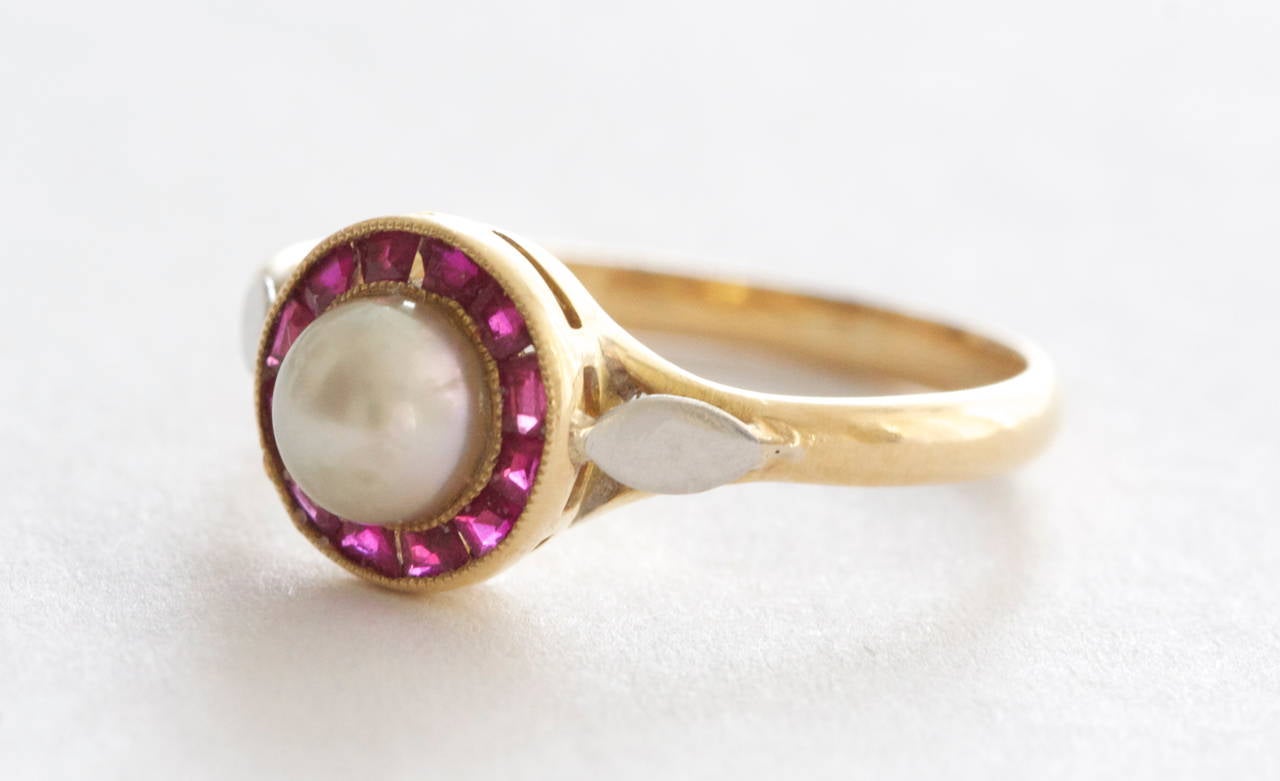 A well balanced combination of a central natural pearl embraced by a dozen colorful red rubies. Crafted in 18k gold and stamped with French hallmarks. 

Ring Size 6 and can be re-sized.