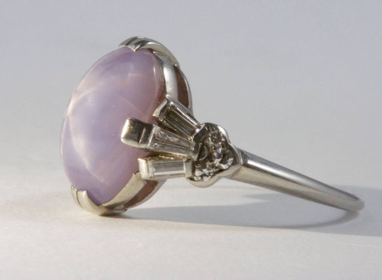A bright star is evident in this 9.50 carat true lavender colored cabochon star sapphire. Set in a classic platinum art deco ring featuring 6 white baguette cut diamonds and 6 white round cut diamonds.

Ring size 6 and can be re-sized.