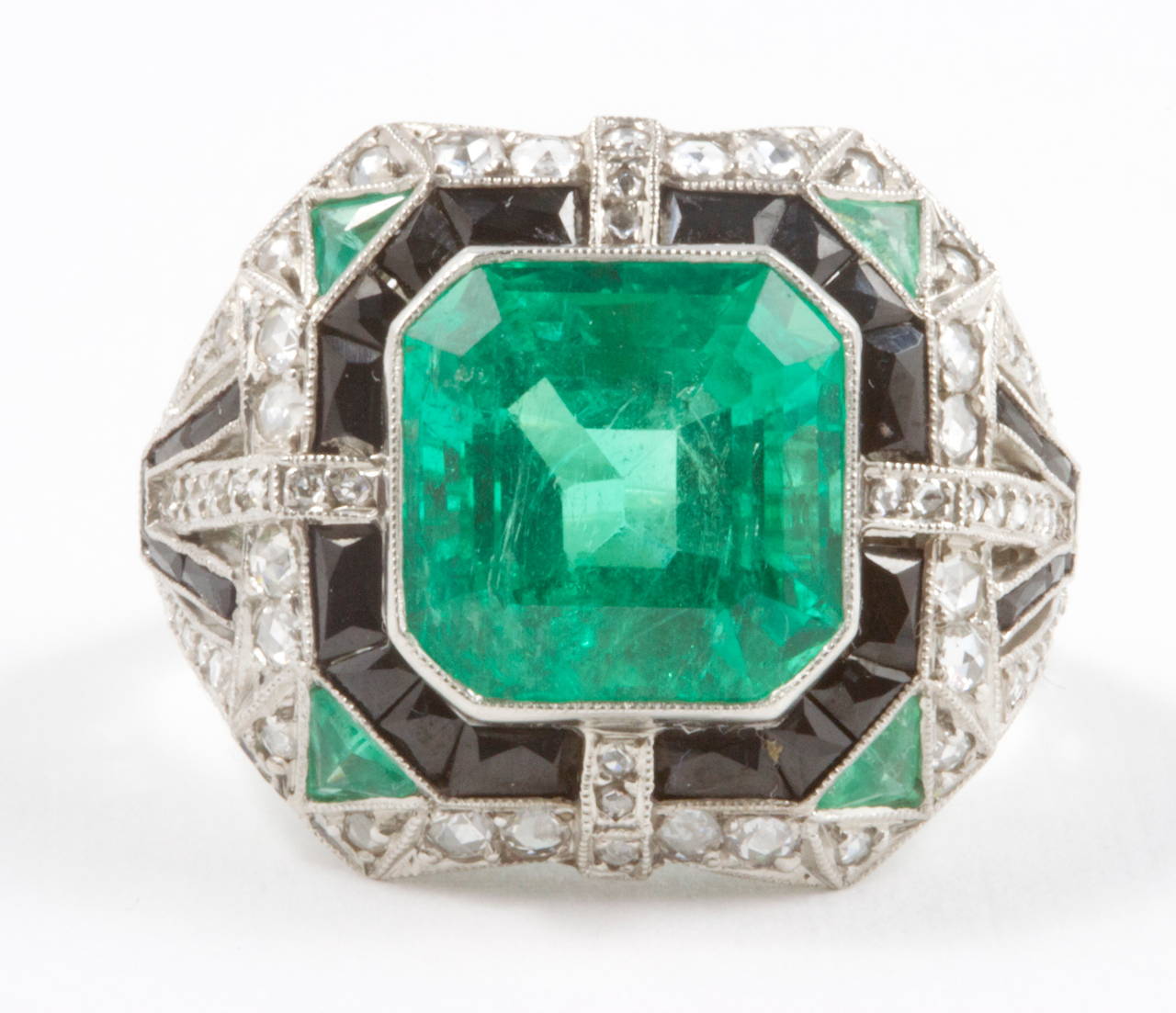 An outstanding AGL certified 6.11 carat colombian emerald that has the deep pure green color desirable in gem quality emeralds.  Bezel set in an expertly handcrafted platinum ring  creatively designed with onyx, diamonds and emeralds. A true work of