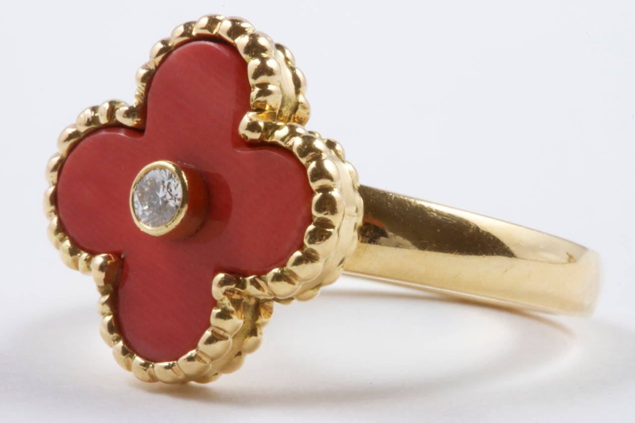 The classic vintage Alhambra ring with its most popular coral design. The ring has been fashioned with a center white diamond and has been created out of 18k yellow gold. 
Signed VCA and numbered.