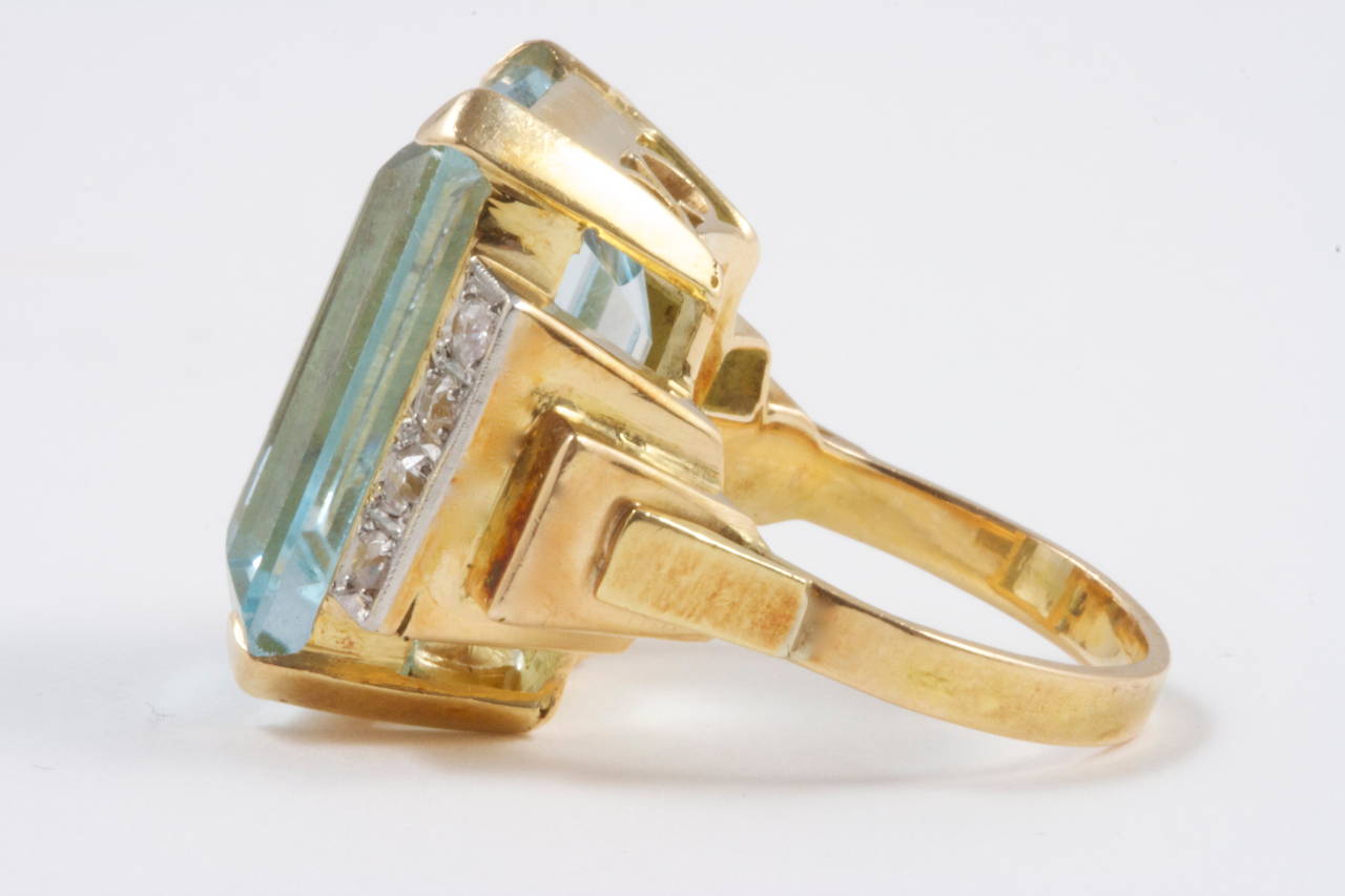 A pleasing retro ring featuring an approximately 15 carat soothing blue aquamarine which has been accented by a row of 4 white, clean diamonds on either side. Hand Crafted in an 18k yellow gold ring.

Size 5-3/4 and may be resized.