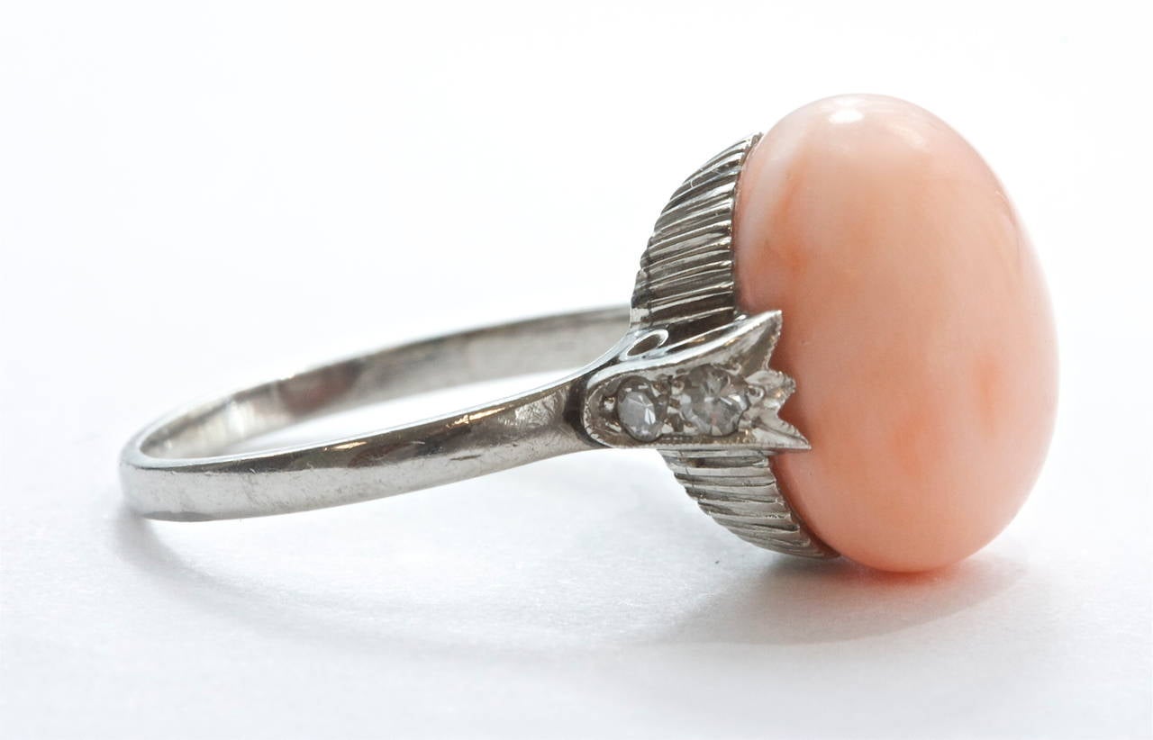 A beautiful Art Deco ring with a cabochon Angel Skin coral in the center.  Set in 14k gold with accenting single cut diamonds.  

Ring is size 7 and can be resized.