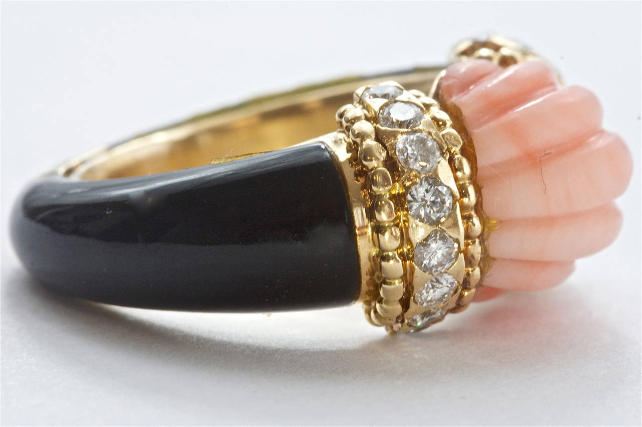 An inspiring ring by French Masonry Boucheron.  The center carved Angel Skin coral is set in textured 18k gold surrounded by diamonds.  The rest of the gold on the ring is covered by black onyx. 

Signed Boucheron with French marks.

Size 4 3/4