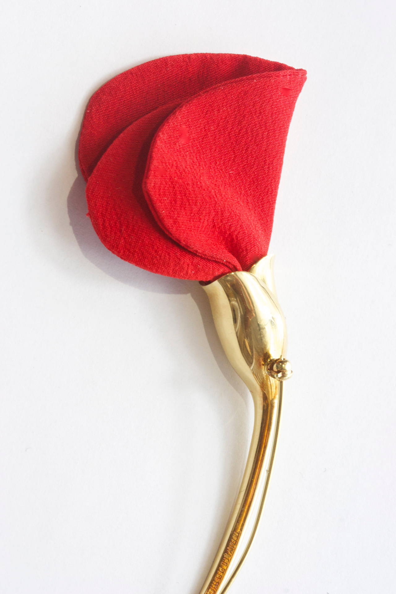 The rose brooch is designed by Peretti. The stem is crafted in 18k yellow gold and the petals are durable but soft smooth red cloth. May also be worn on a jacket lapel for men or women.