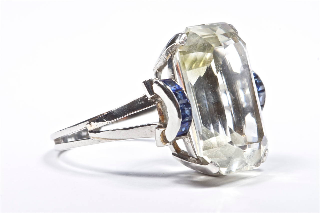 The light natural aquamarine weighs approximately 14.00 carats and is perfectly complimented by the deep blue of the channel set sapphires. The stones are set in a hand made well designed platinum mounting.

Size 7 1/2 and can be re-sized.