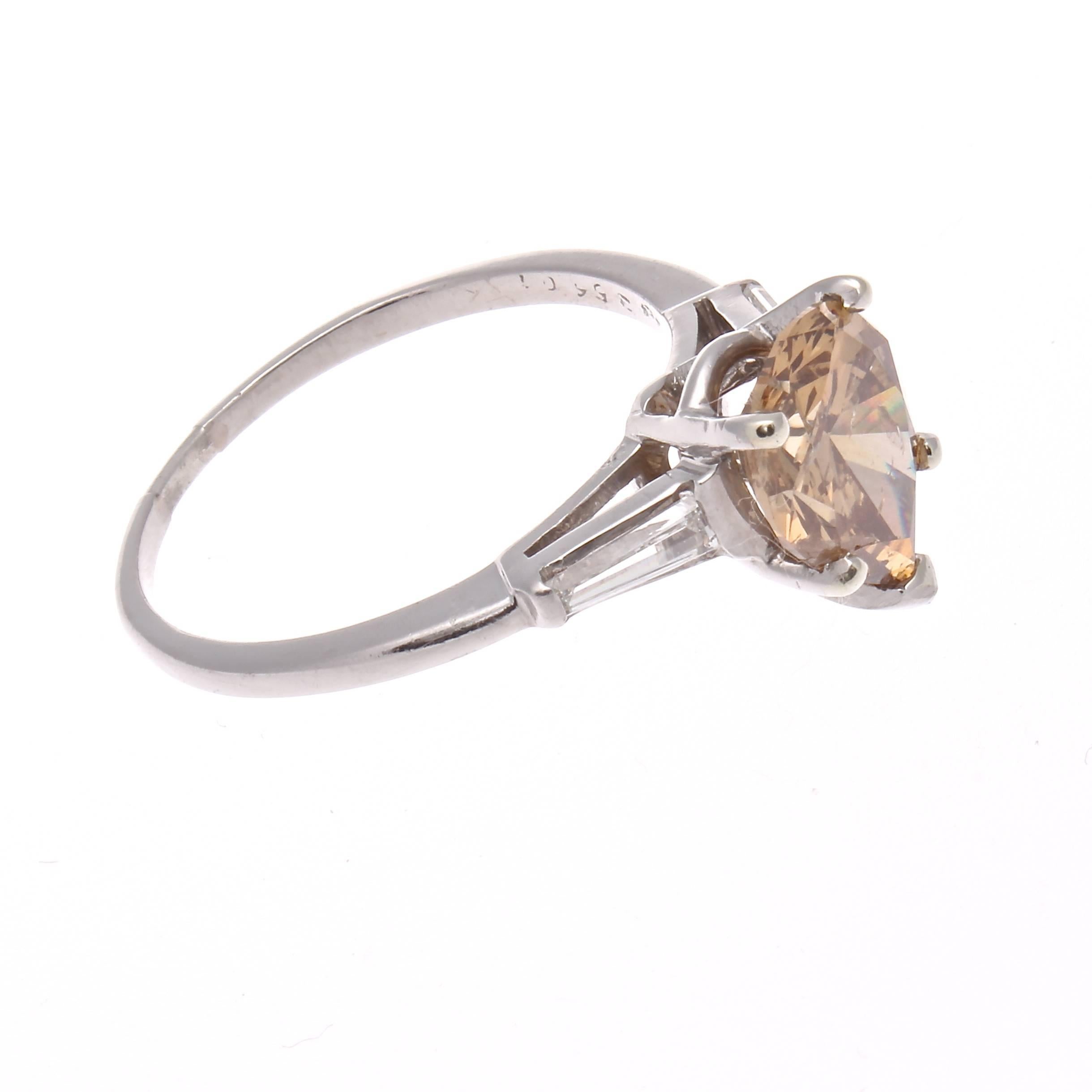 A beautifully realized modern engagement ring featuring a vibrant 2.00 carat pear shaped champagne colored diamond. Accented by two clean, white baguette cut diamonds and hand crated in a platinum ring.

Ring size 8-1/4 and may be resized