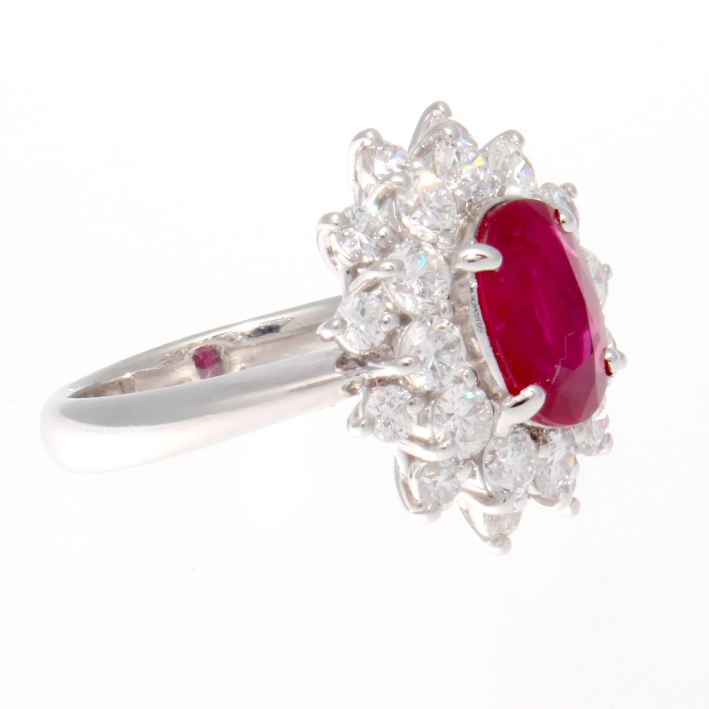 A natural 3.03 carat gem quality ruby has been AGL certified as Burmese origin with indications of heat treatment. The deep rich red oval cut ruby has been surrounded by a blooming flower motif of near colorless round cut diamonds. Hand crafted in