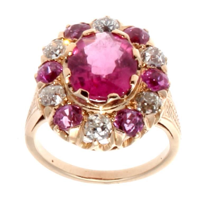 A lovely color combination featuring vivid pinks and bright whites. The featured bright pink rubellite center has been surrounded by a supporting cast of pink sapphires and white, clean diamonds in the classic halo style. Hand crafted in an 18k rose