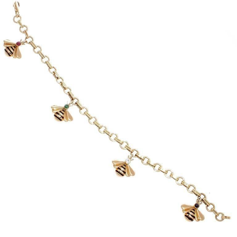 Un design moderne signé Cartier. Il s'agit de quatre breloques en forme de bourdon qui voltigent et qui sont conçues avec des bandes d'émail et des têtes en diamant:: émeraude:: rubis et saphir. Fabriqué en or jaune 18k. Signé Cartier:: numéroté et