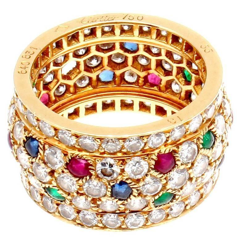 A vibration of color radiates from this ring with brilliance and design from Cartier. Fashioned with a puzzle of diamonds, emeralds, rubies and sapphires that fit perfectly with symmetry and balance. Crafted in 18k Gold. Signed Cartier, numbered and