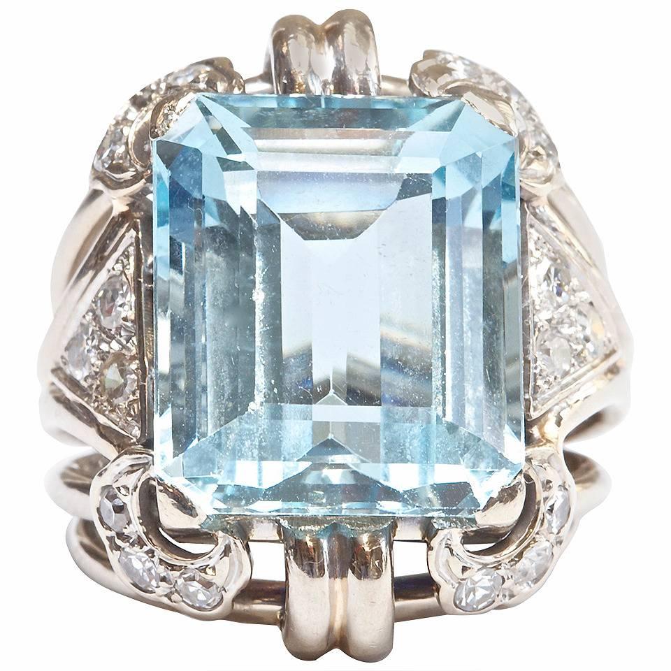 The hand made 18k gold ring has been created with 6 separate conjoining bands meeting at the bottom of the ring. With 18 white single cut diamonds as accents surrounding the approximately 22 carat aquamarine.  

Size 6 1/2 and can be re-sized.