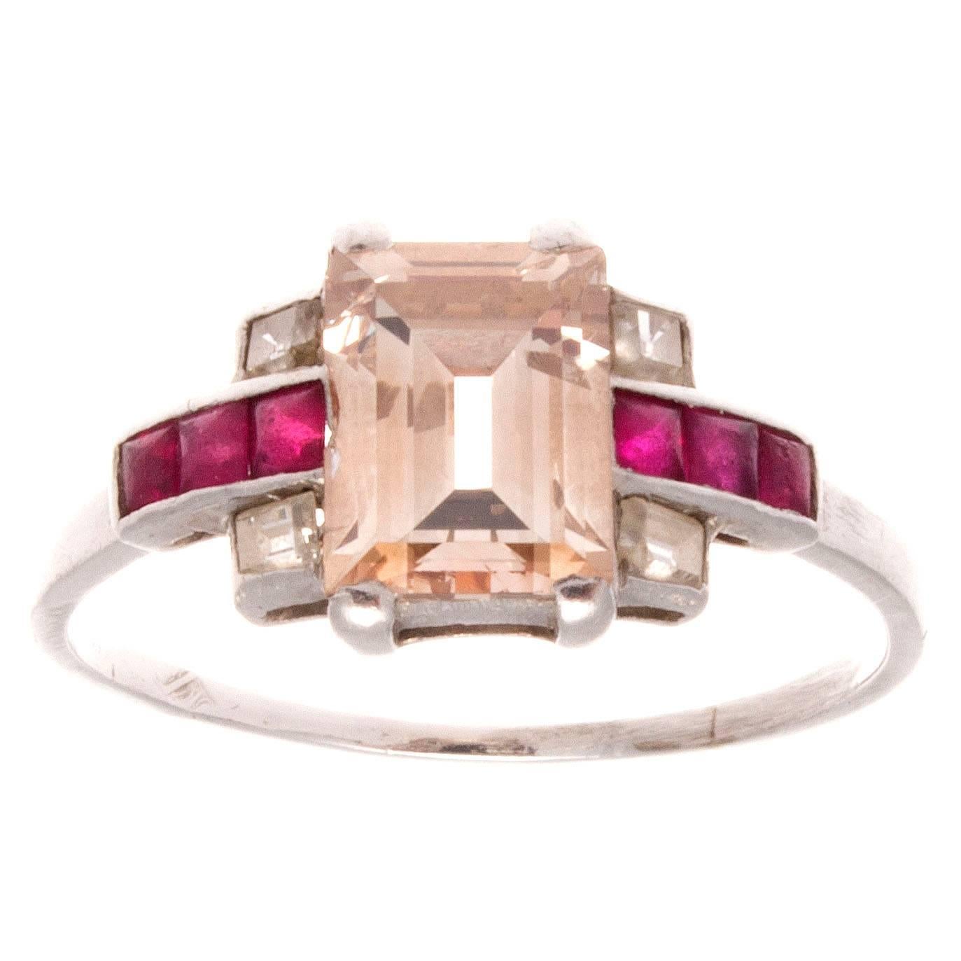 A rare and exciting Art Deco ring. The center emerald cut diamond weighs 1.35 carats and the accenting rubies beautifully reflect the warmth of the light pinkish brown color. As an engagement ring, that warmth expresses the best wishes for a happy