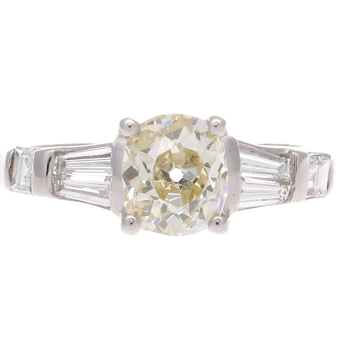 A charming creation of clean elegance. Featuring a 1.18 carat center diamond that has a warm yellow tinge. Accented by white, clean baguette and square cut diamonds. Hand crafted in platinum.