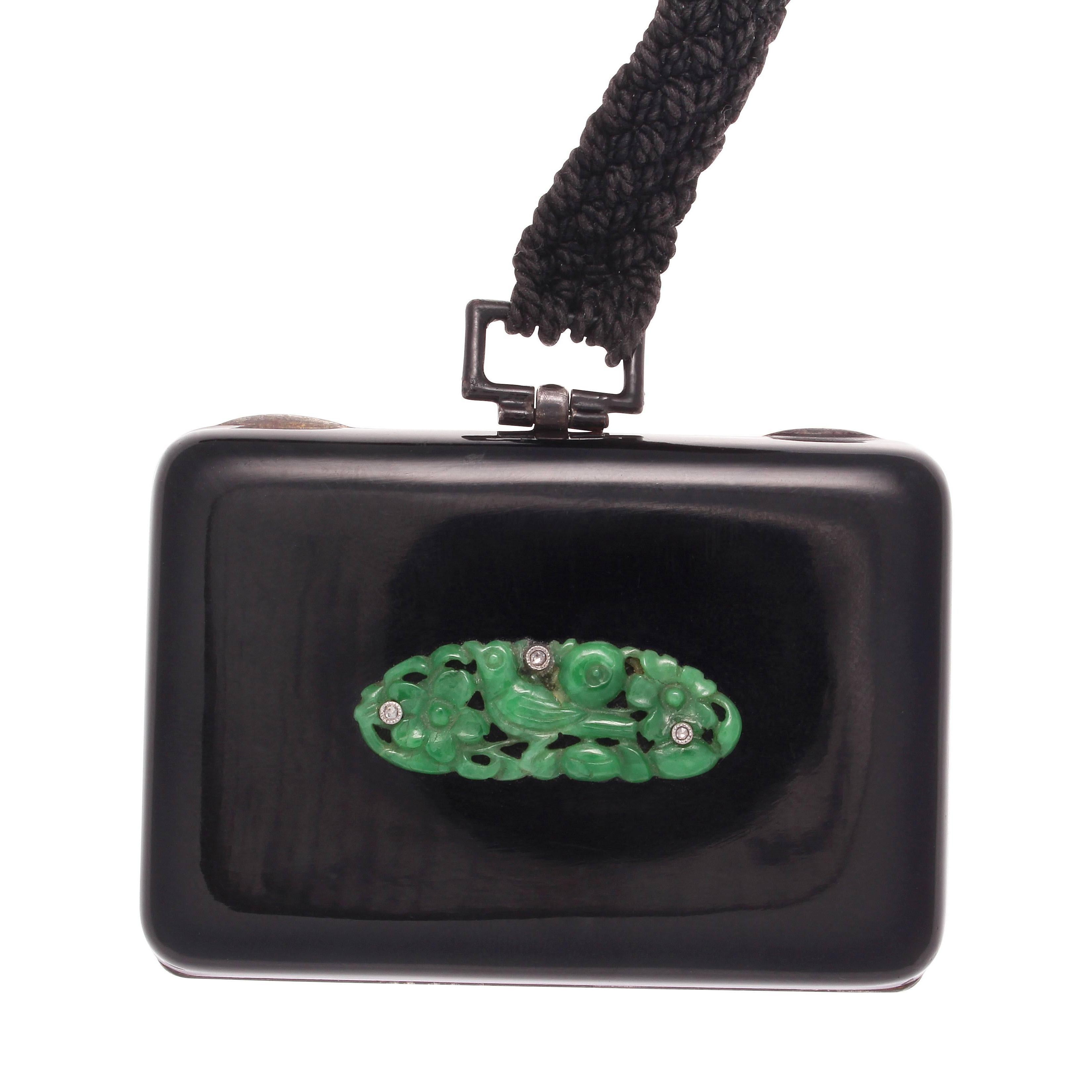 Style is something that never lacks in the creations of French designers. A lovely compact with jet black enamel coating the 18k gold box. The carved jade depicts a bird feeding in a green garden filled with diamonds. Stamped with French hallmarks.