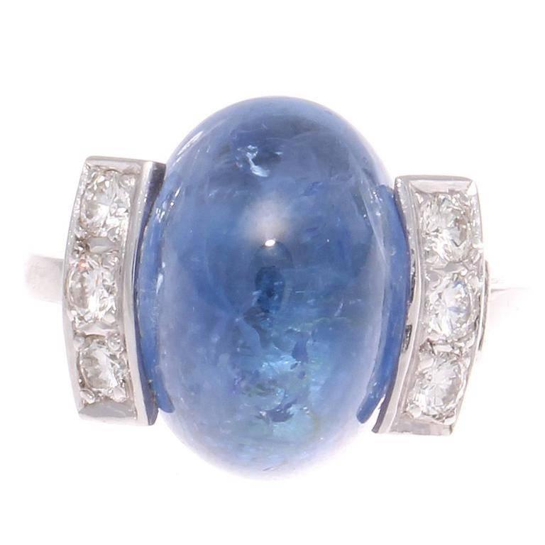 A lovely translucent ocean blue cabochon cut sapphire weighing approximately 17 carats has been perfectly complimented by two tiered rows of lively white, clean diamonds on either side. Hand crafted in platinum. Signed with French hallmarks. 