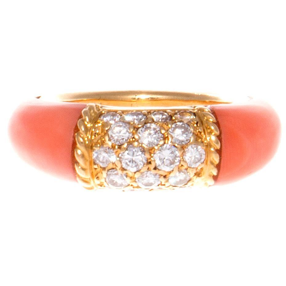 The classic Philippine ring from Van Cleef & Arpels. Designed with pave set diamonds in textured 18k yellow gold accented by glowing angel skin coral cascading down either side. Signed VCA, numbered and stamped with French hallmarks.

Ring size 5