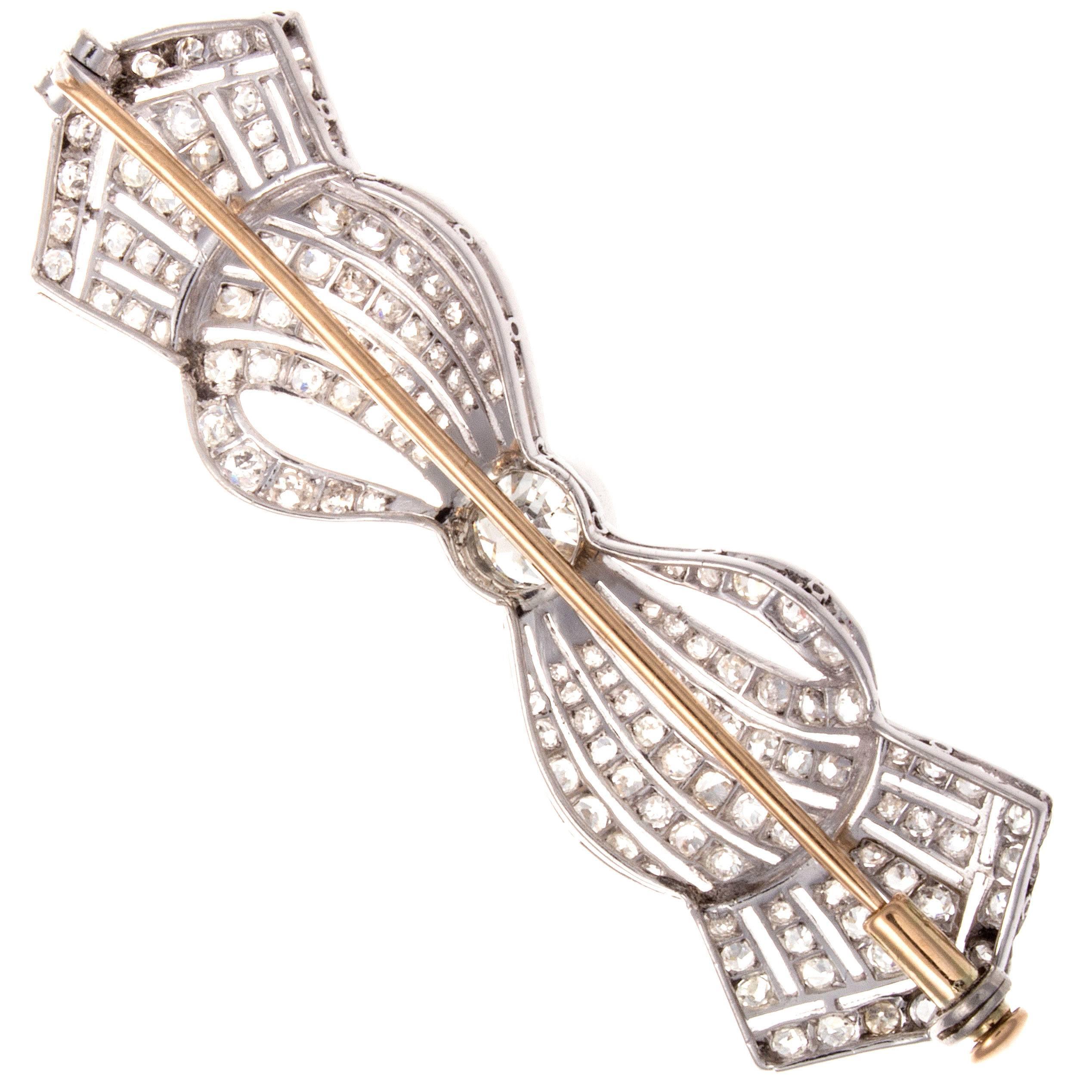 A smooth rhythmic art deco designed brooch that flows with fabric like ease. With an old European cut clean, white center diamond that weighs approximately 0.65 carats and is accented by 140 old cut diamonds weighing approximately 3.00 carats. Hand