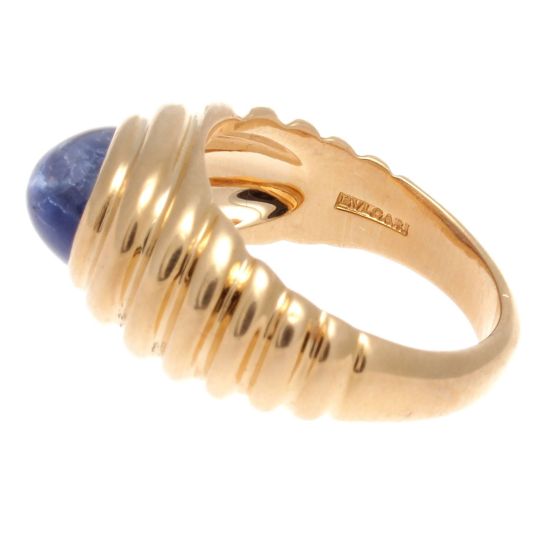 An alluring creation of color and design from Bulgari. Featuring a translucently vibrant blue cabochon cut sapphire uplifted by ascending contours of 18k yellow gold. Signed Bulgari.