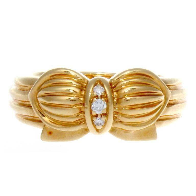 France has always been recognized for its style and fashion and the jewelry created there is no exception. The ring is designed with three near colorless diamonds and fashioned with rolling contours of 18k yellow gold creating this bow motif. Signed