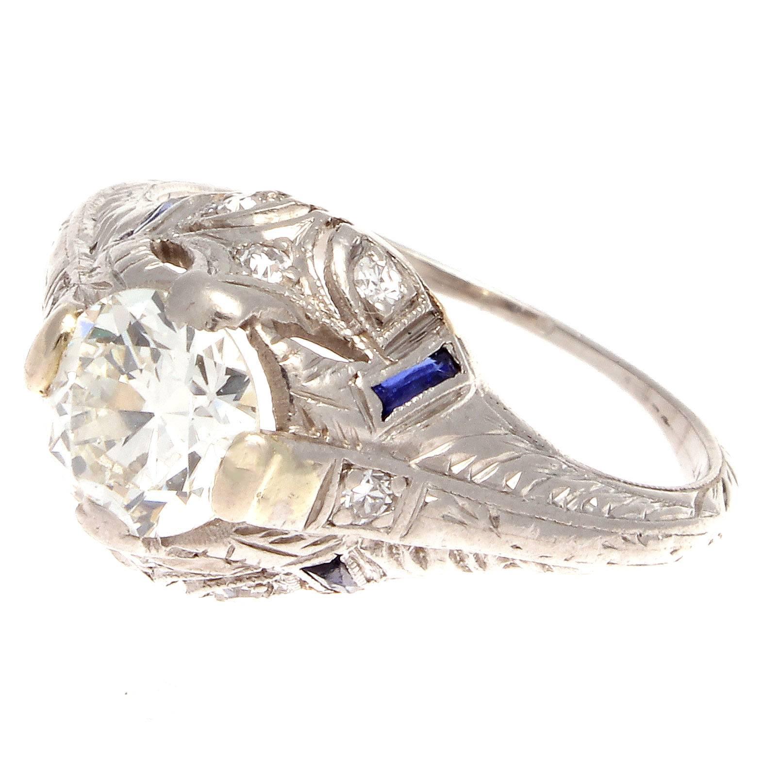 The architectural design and attention to detail makes this engagement ring undeniably Art Deco. Featuring a 0.75 carat old European cut diamond that is I color, VS+ clarity. Perfectly complimented by well placed blue sapphires and excellently