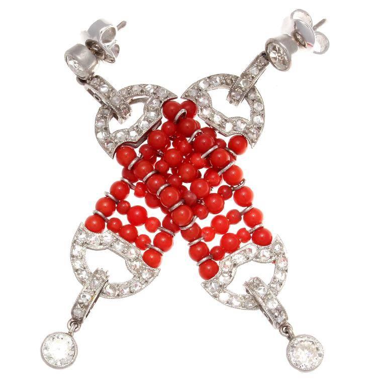Inspired by one of the most prominent jewelry periods in history, the Art Deco era. Bursting with color the vibrant reddish-orange coral plays a perfect complement to the elegantly designed diamond drops. Hand crafted in platinum.