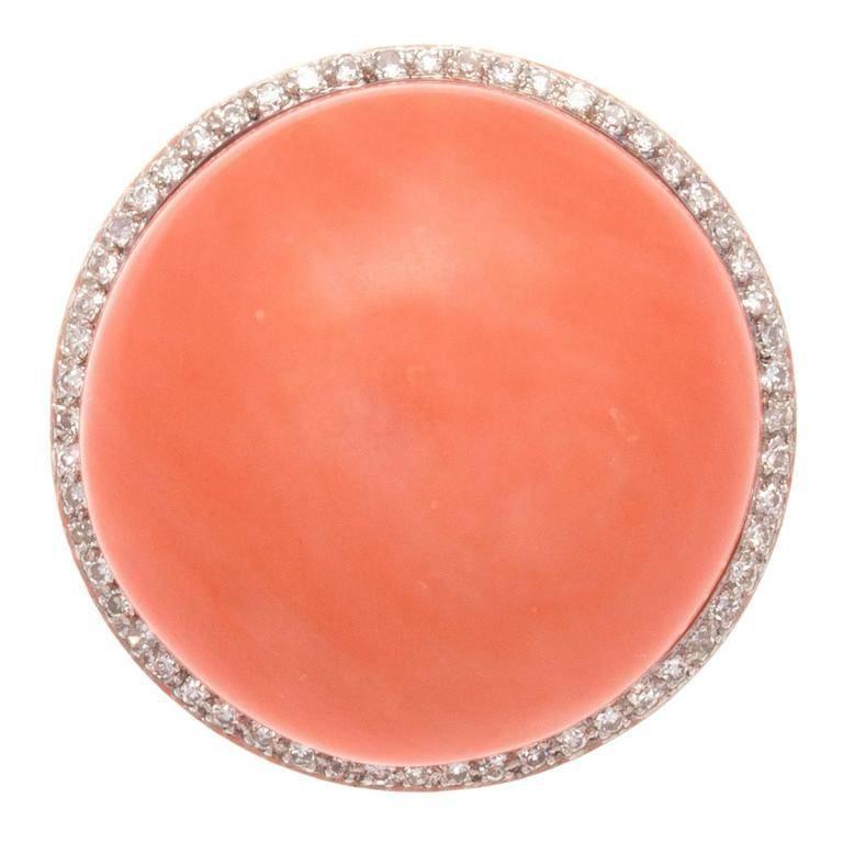 A retro creation that is true to its larger than life time period. Designed with substantial large orangish-red cabochon cut coral and surrounded by a halo of clean, white diamonds. Hand crafted in an intricate 14k white gold design.  

Diameter 1