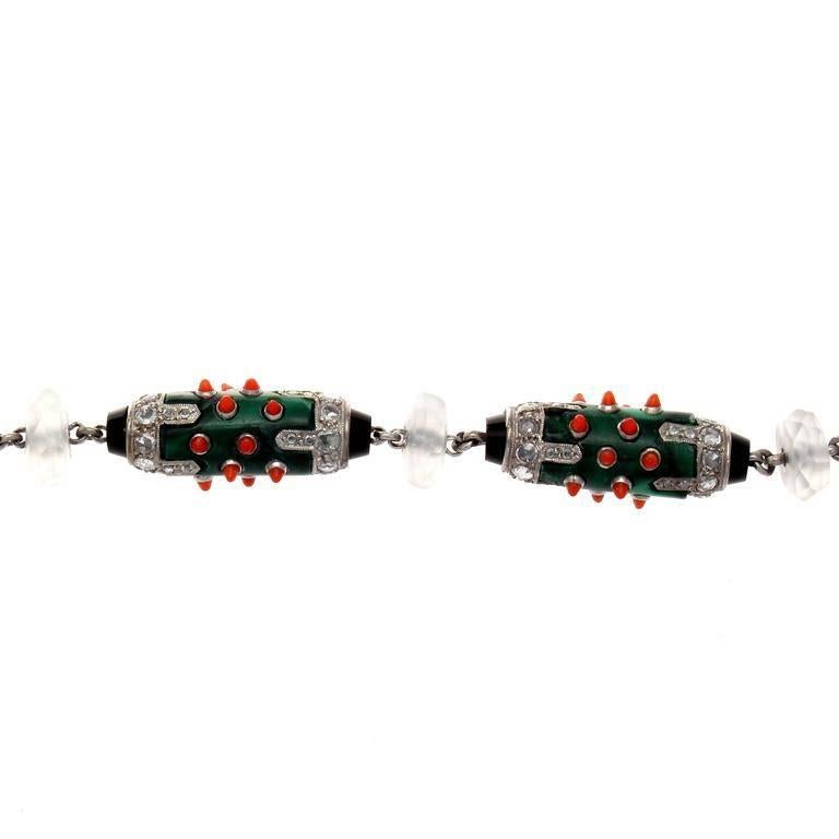 A unique creation inspired by the iconic art deco time period. Created with an array of gleaming colors coming from links of deep green malachite that is superbly complimented by bright orange cabochon cut coral and accented by clean, white diamonds