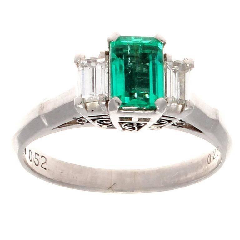 A lovely and colorful modern rendition of the traditional engagement ring. Featuring a crisp and lively green 0.52 carat emerald that is accented by 2 colorless diamonds weighing 0.25 carats. Weights are inscribed. Crafted in platinum.

Ring size