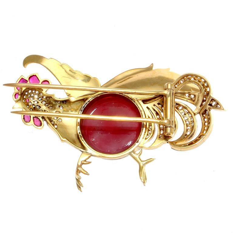 A charming and colorful creation that captures the rooster in mid flight. Decorated with a large vibrant red carnelian that has been complimented by numerous near colorless diamonds and lively pink rubies. Hand crafted in 18k yellow gold.