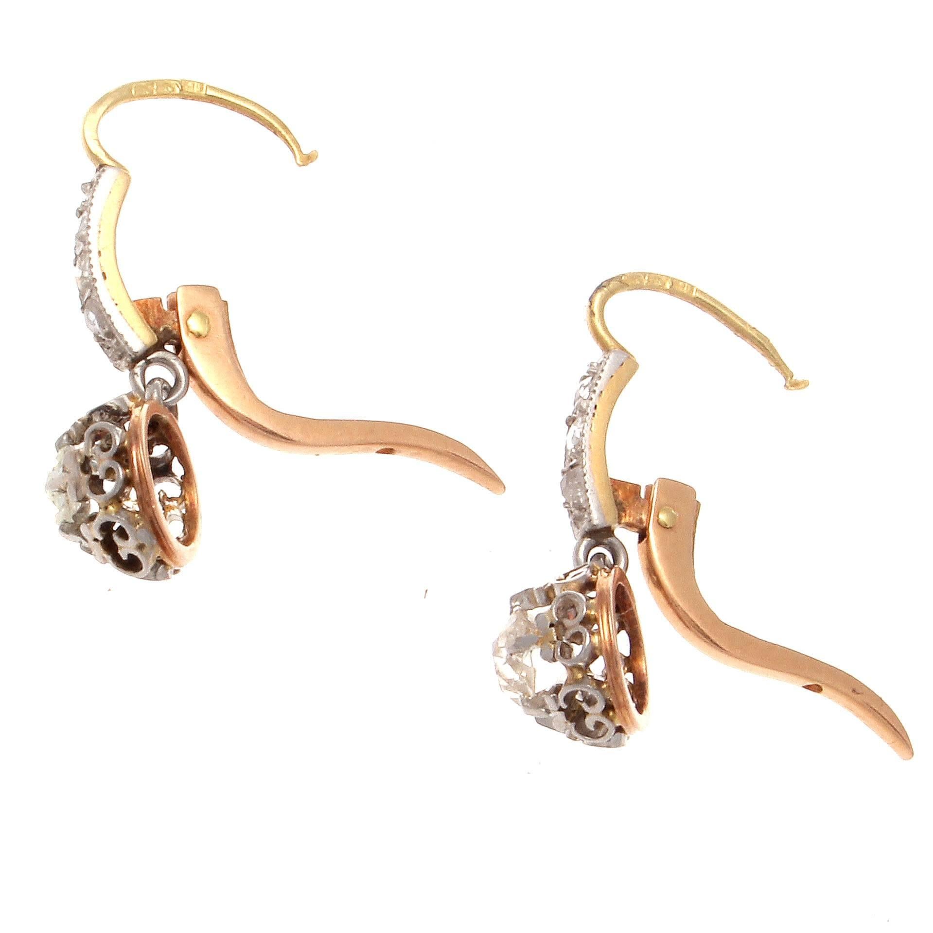 True to its distinctive belle epoque style. These earrings have been designed with gently cascading diamonds leading to the superior hand crafted drops. Featuring elegant platinum and gold design uplifting two old cushion cut diamonds weighing