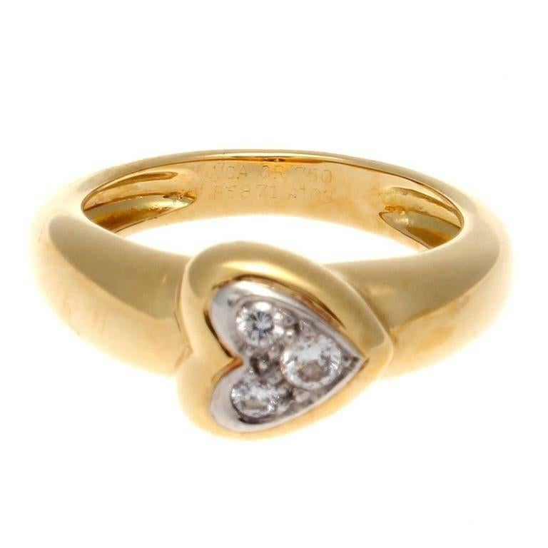 Van Cleef & Arpels, a long rich history of trend setting fashion that is still relevant today. This ring has been fashioned with three near colorless diamonds to create an embracing heart motif. Crafted in 18k yellow gold. Signed VCA and