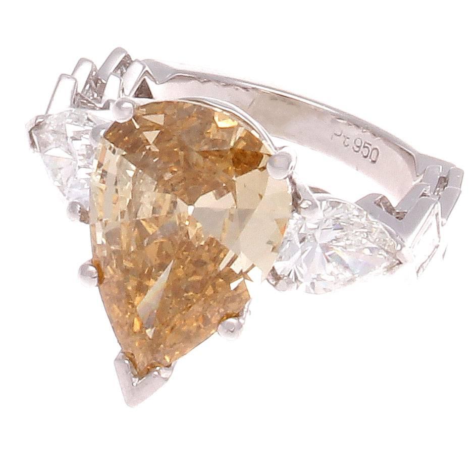 A modern rendition on the traditional engagement ring. Featuring a GIA certified nautral 3.72 carat fancy deep brown-yellow pear shaped diamond that is VS2 clarity. Accented by two colorless pear shape diamonds that weigh 1.25 carats together and